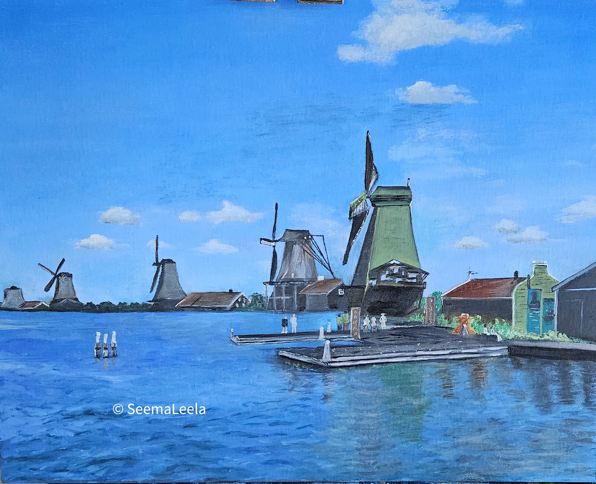 A serene landscape of windmills by the water under a blue sky.