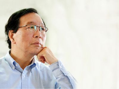 Thoughtful man wearing glasses and a blue shirt looking away.