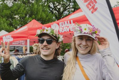 Two people smiling with floral hats at an outdoor event.