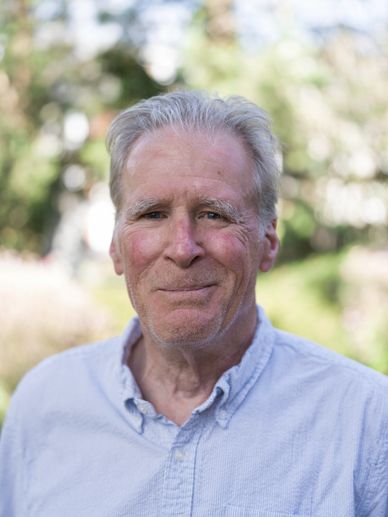 Smiling elderly man outdoors in a light blue shirt.