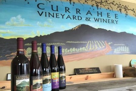 Photo of some Currahee wines in front of a mountain painting at the distillery.
