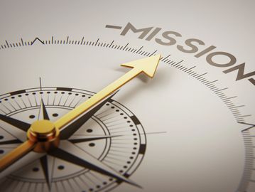 A compass with the dial pointing at the word "Mission".
