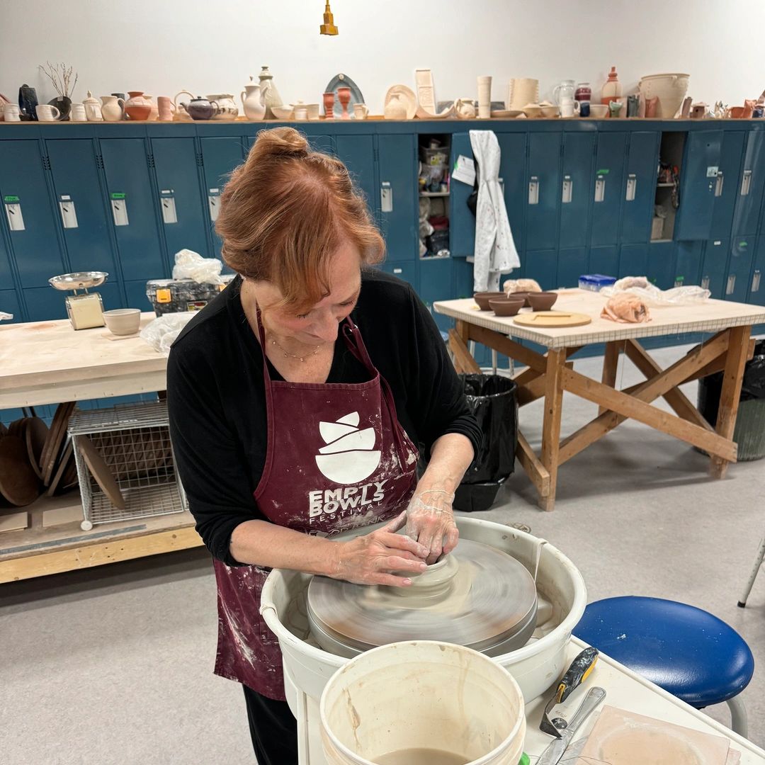 Woman shaping clay on a pottery wheel in a studio.