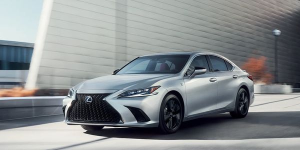Silver Lexus sedan driving on a city street.
