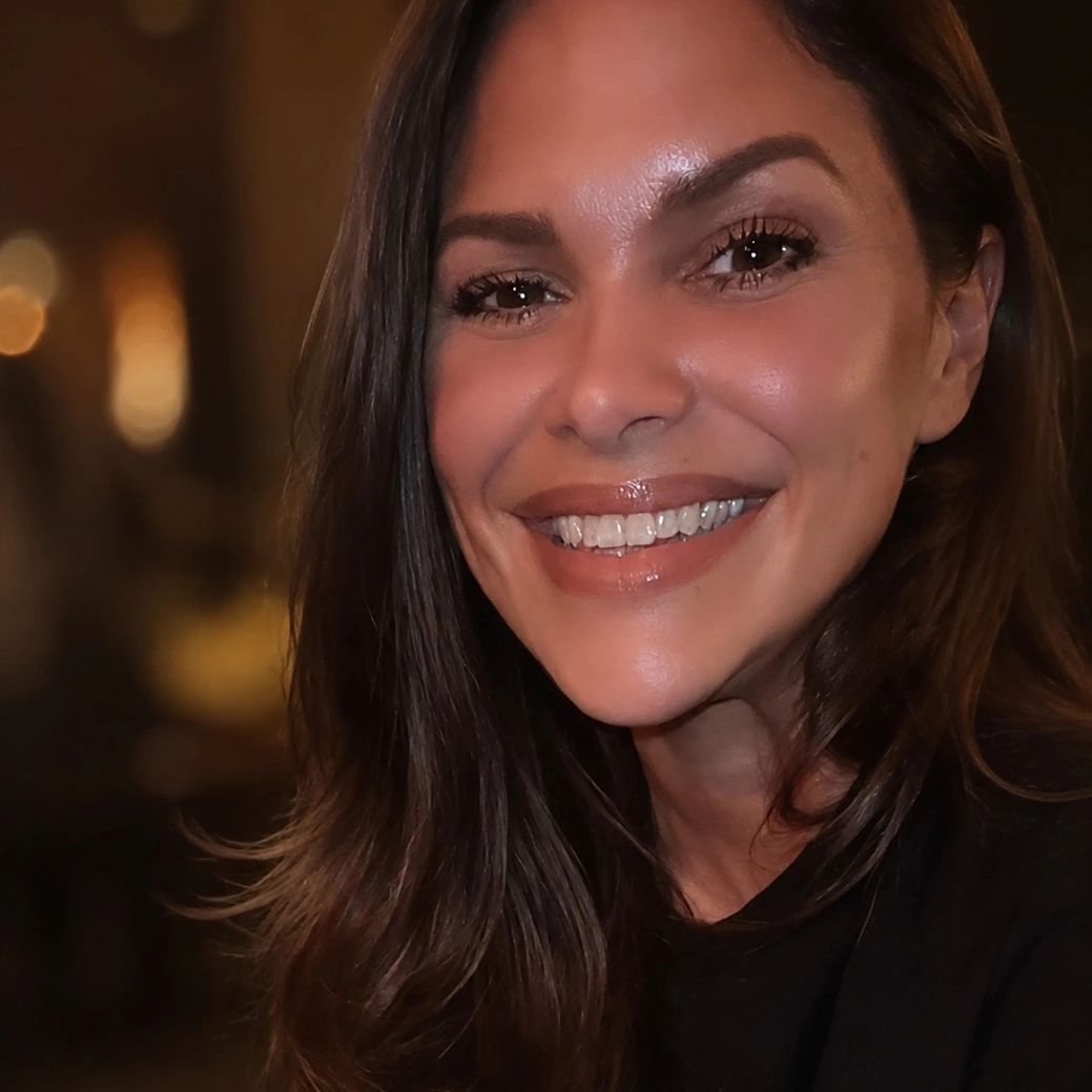 Close-up of a smiling woman with long dark hair.