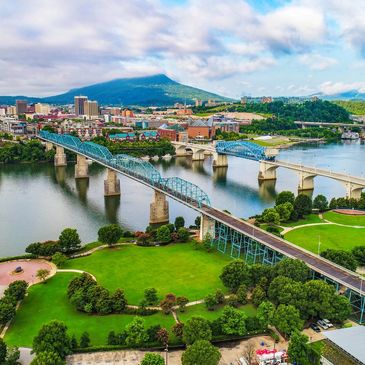 A scenic cityscape with bridges over a river and a mountain in the background.
