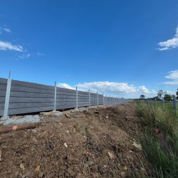 Long gray fence under blue sky.