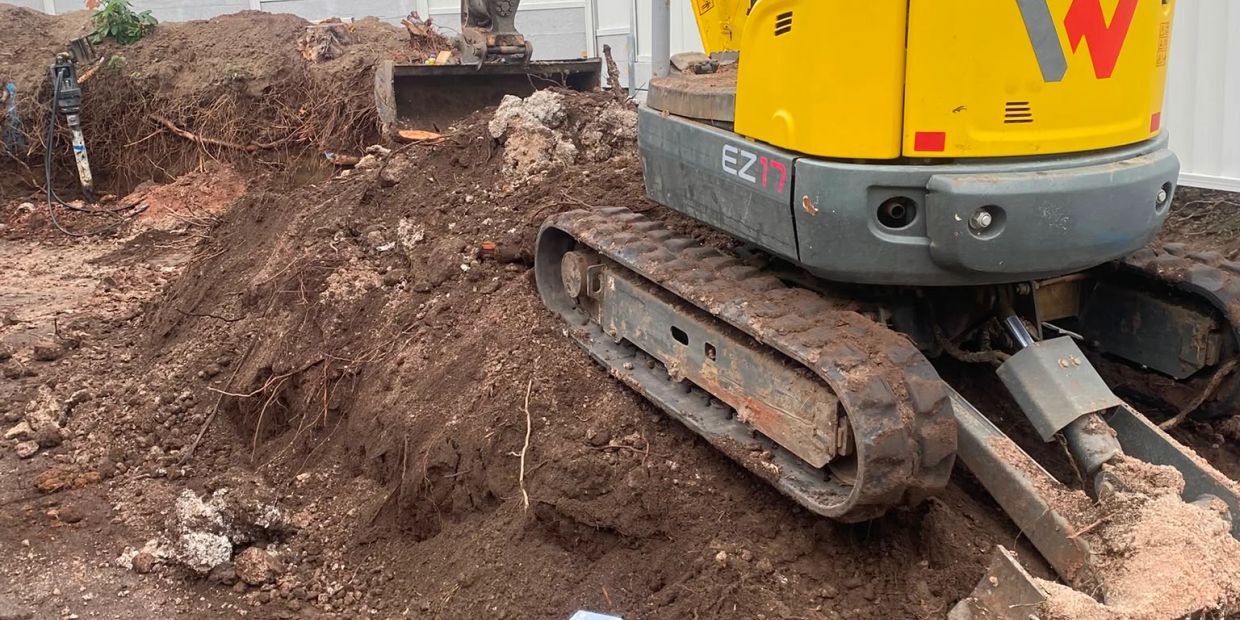 Tracked excavator digging soil at a construction site.