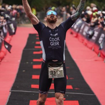 A triumphant triathlete crossing the finish line with arms raised.