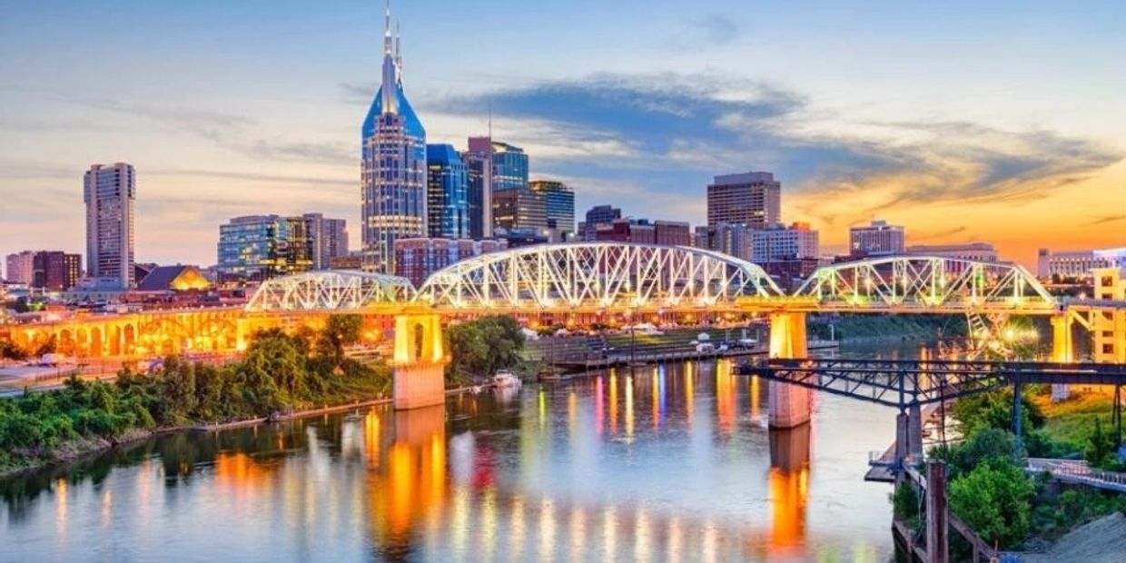 City skyline with illuminated bridge at sunset.