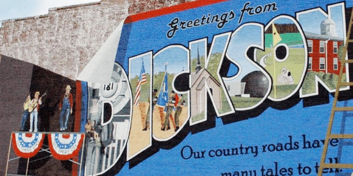 Mural with "Greetings from Dickson" and people painting it.