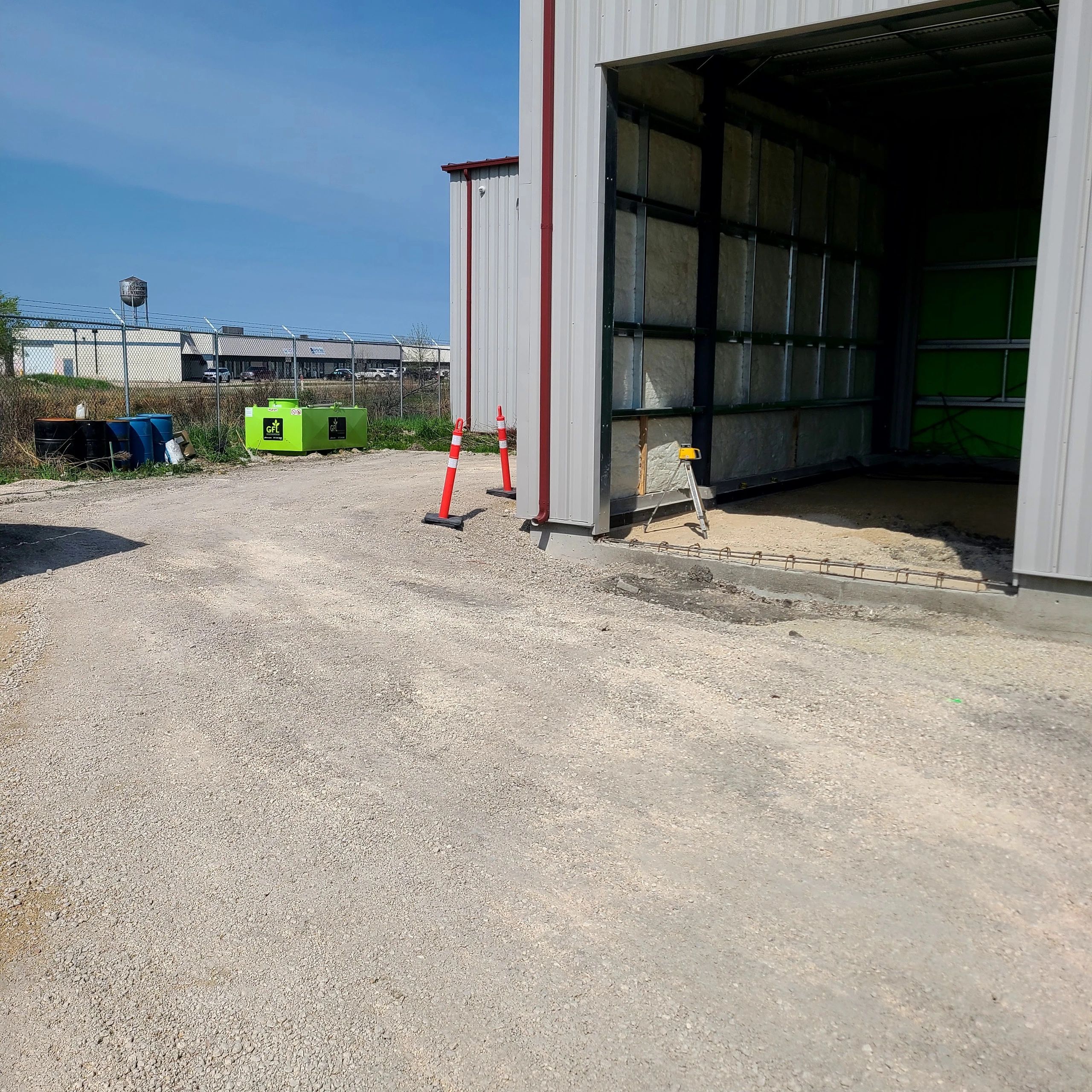 Outdoor industrial area with barrels and construction equipment.