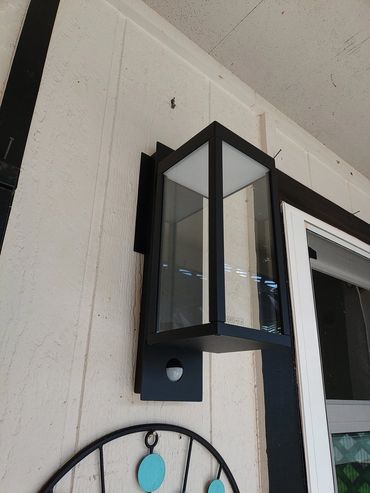 Modern outdoor wall lantern mounted by a door.