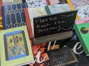 Handmade healing journals displayed with a sign asking not to touch them.