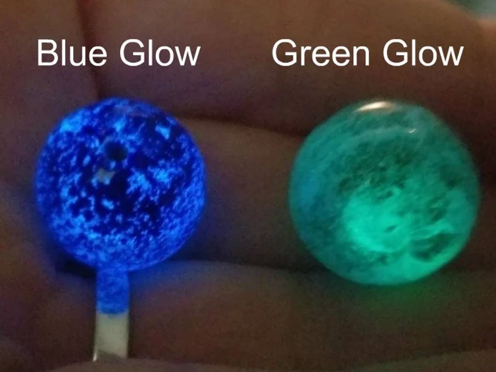 Two glowing spheres, one blue and one green, held in a hand.