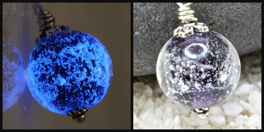 Close-up of a glowing blue and a clear glass pendant with internal speckles.