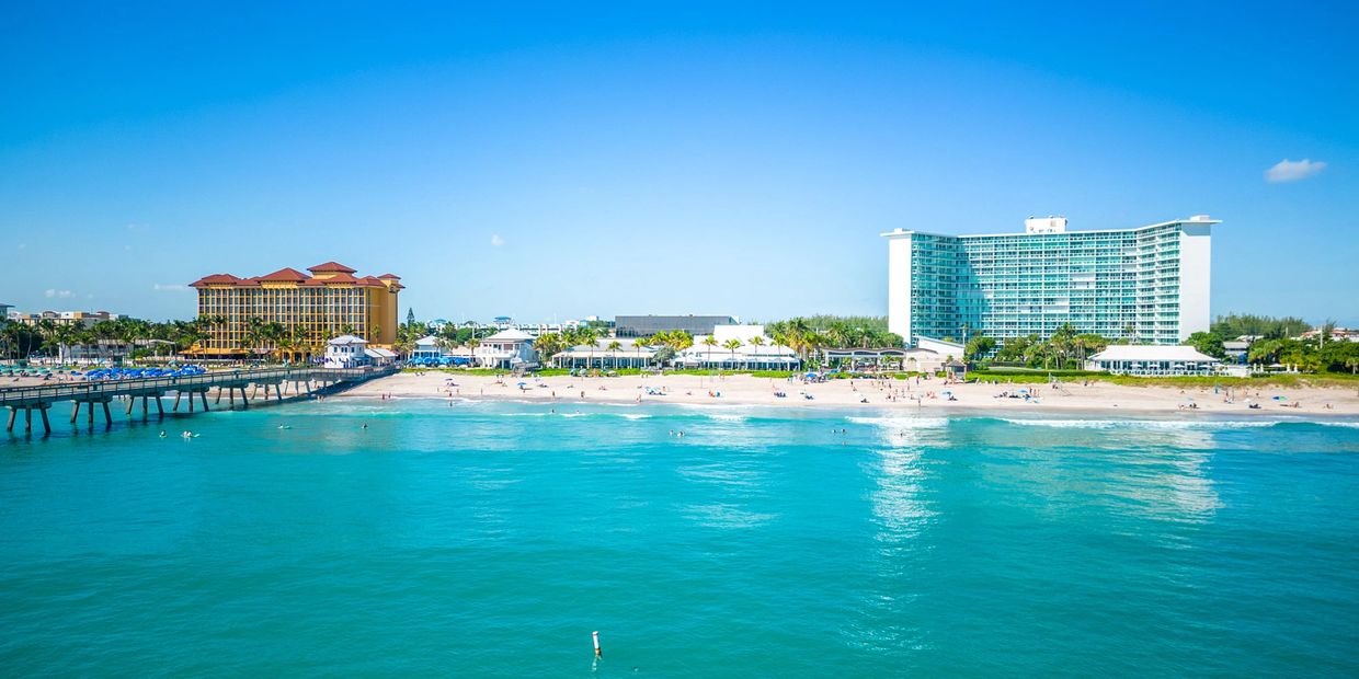 A sunny beach with hotels and turquoise ocean water.