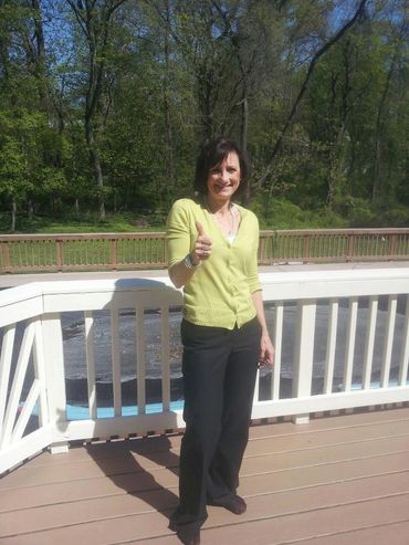 A smiling woman giving a thumbs up sign, standing on her new deck with rails