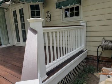 Beautiful wooden porch, stained brown with white pickets and posts and brown handrails.