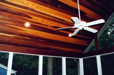 A beautifully stained natural wood ceiling and ceiling fan in a Screened Addition