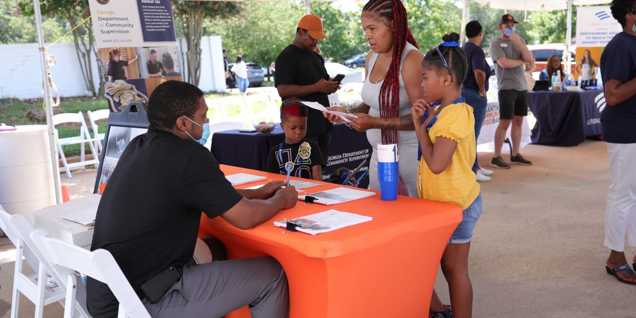 People engage at a community resource fair with informational tables.