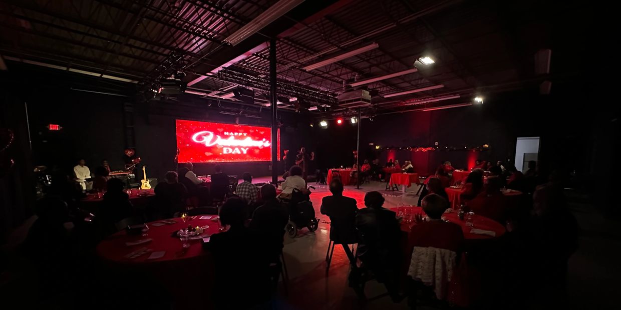 Audience watching a Valentine's Day event in a dimly lit venue with red décor.