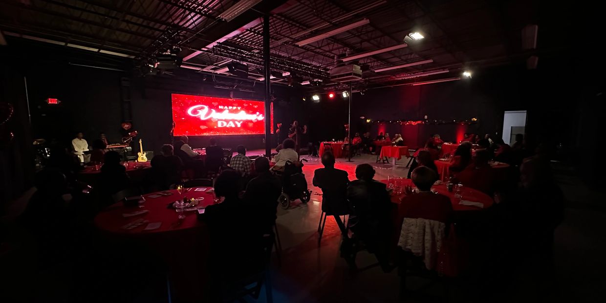 Audience watching a Valentine's Day event in a dimly lit venue with red décor.
