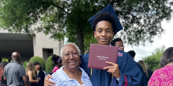 Young graduate holding diploma with an elderly woman.