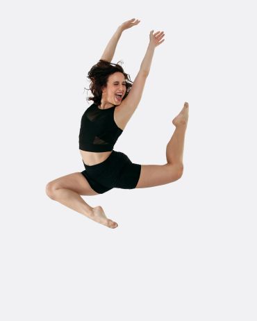Woman joyfully jumping in dance attire.