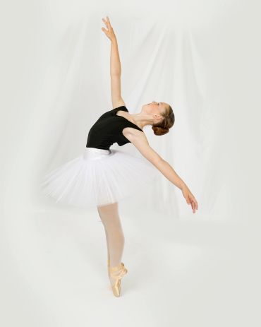 Ballet dancer in white tutu and black top on pointe.