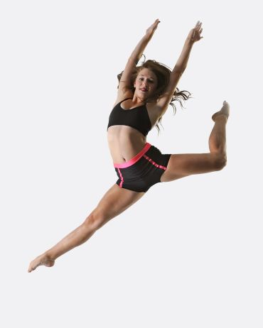 Woman dancing mid-air in athletic wear.