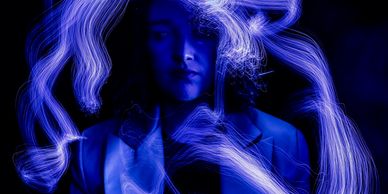 Person surrounded by blue light trails in a dark setting.