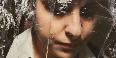 Person behind a translucent plastic sheet, appearing contemplative.
