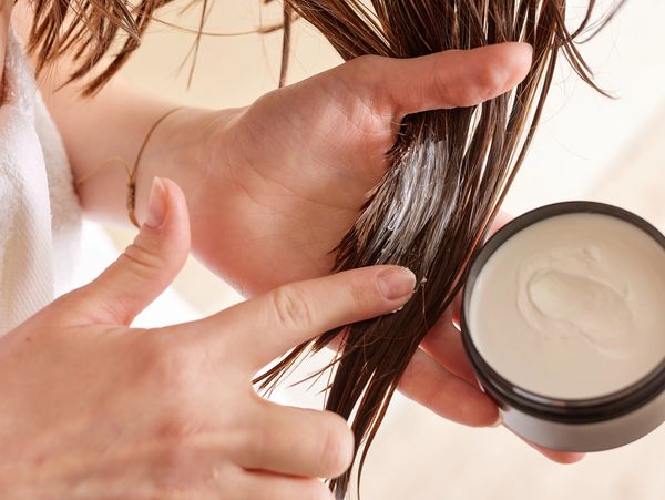 Hands applying product to hair.