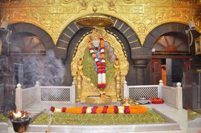 Statue adorned with garlands in a golden shrine with smoke and fire.