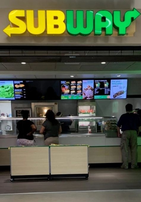 Subway restaurant counter with menu boards visible.