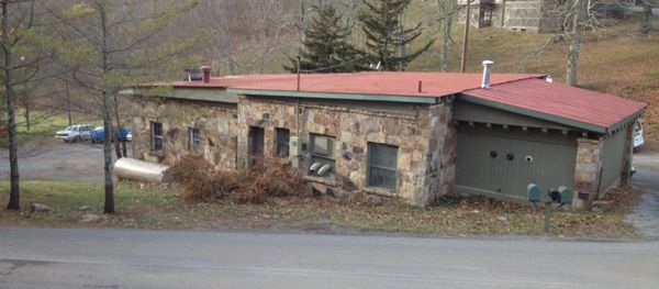 Stone building with old red roof and garage door.