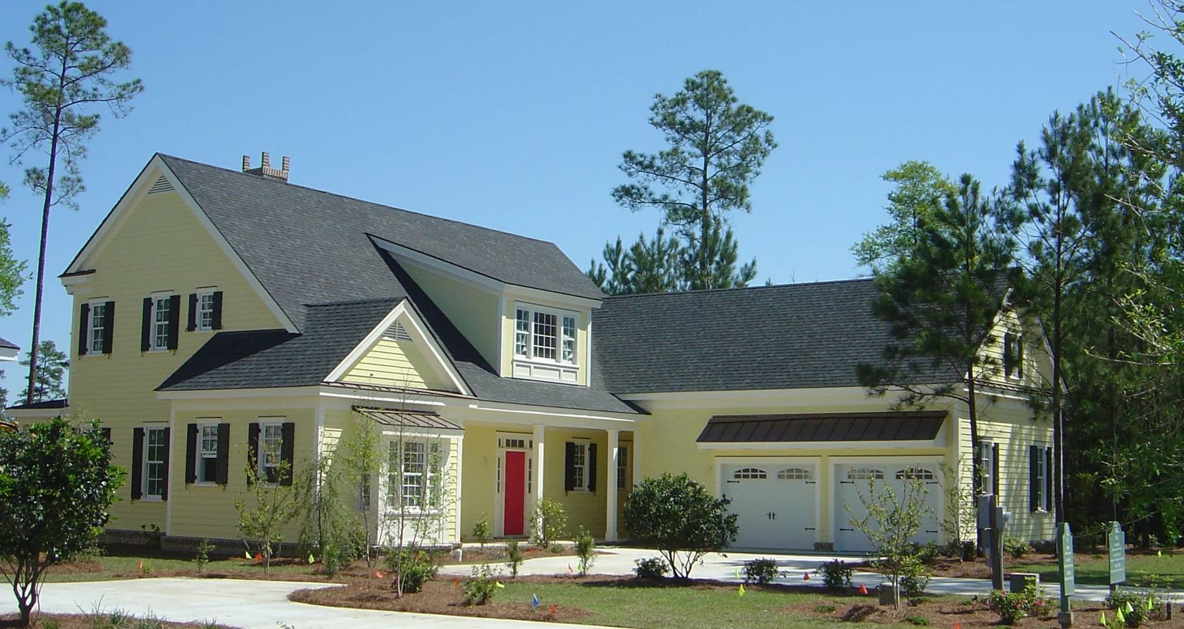 Yellow two-story house with black shutters and porch.