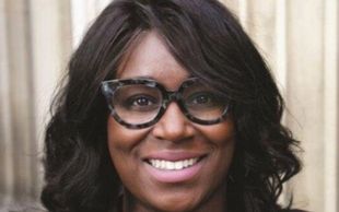 Smiling woman with glasses and curly hair.