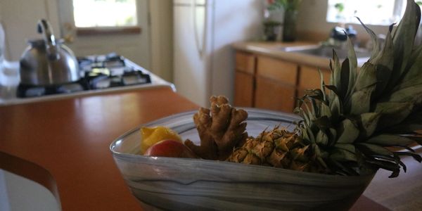 A bowl of assorted fruits and ginger in a kitchen setting.