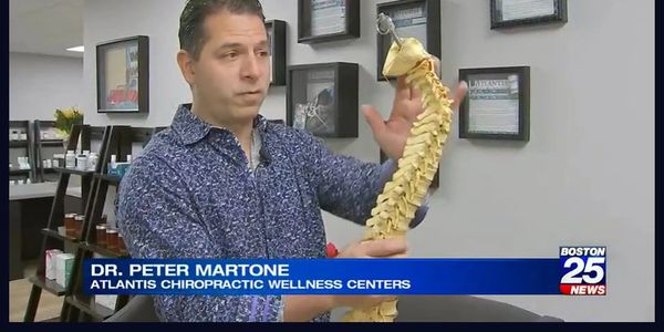 Dr. Peter Martone explains spinal health using a spine model at Atlantis Chiropractic Wellness Centers.