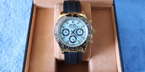 Luxury watch with black strap in a tan box.