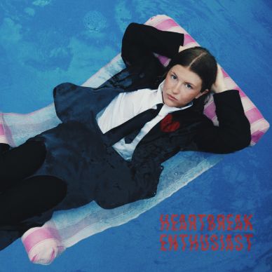 Person in a suit lying on a float in a pool with 'Heartbreak Enthusiast' text.