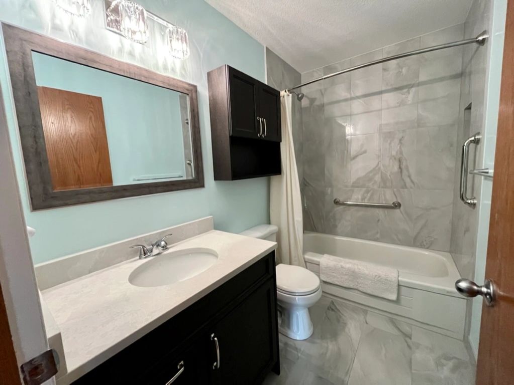 Updated bathroom with matte & polished 12x24. New mirror & vanity light, fresh coat of paint