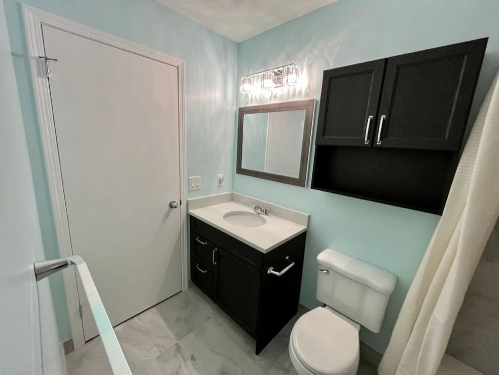 New dark wood vanity & over-john cabinet. Painted white door & trim,  and new tiled baseboards