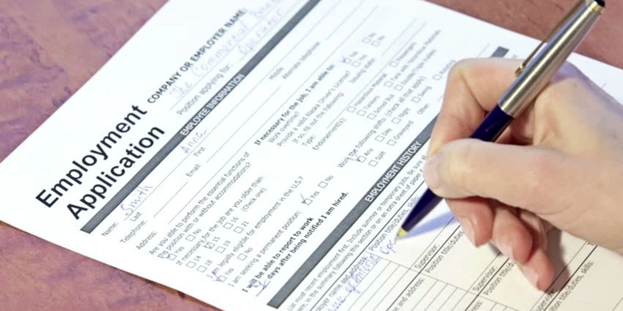 Person filling out an employment application form.