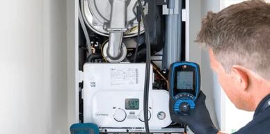 Technician inspecting a boiler unit indoors.