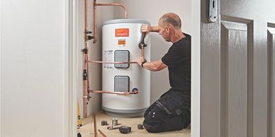 A man installs a water heater with copper pipes.
