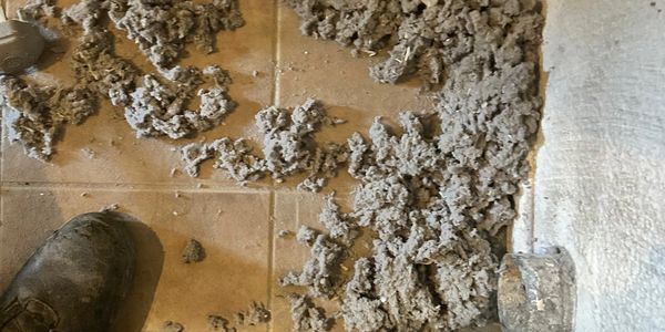 Wet cement being spread on a tiled floor.