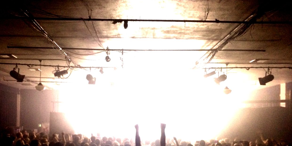 A crowd of people cheering to a bright washed out stage in the historic W.O.W. Hall in Eugene Oregon